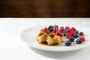 Waffles with fresh ripe berries over a white plate
