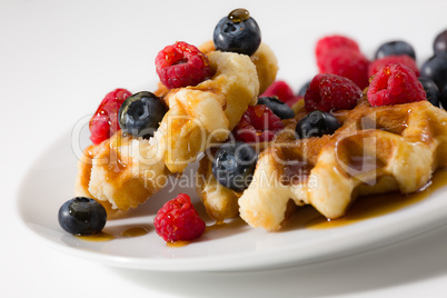 Close-up of waffles with berries and maple syrup