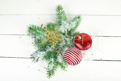 Sprigs of fir and bright Christmas decorations on a white wooden