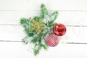 Sprigs of fir and bright Christmas decorations on a white wooden