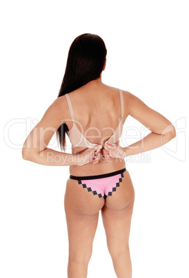 Woman standing in panties, closing her bra