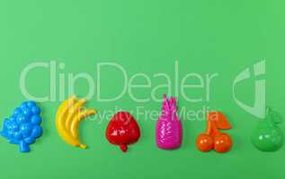 multicolored plastic toys fruits on a green background