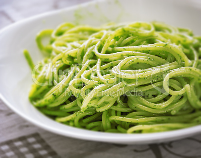 A plate of spaghetti with pesto sauce