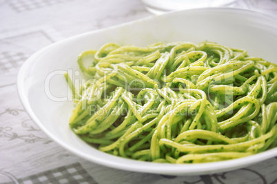 A plate of spaghetti with pesto sauce