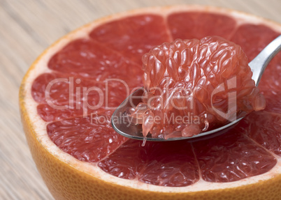 Half of Juicy Ripe Red Grapefruit with slice in a spoon.