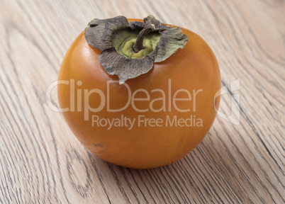 Whole ripe persimmon fruit on wooden background.