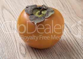 Whole ripe persimmon fruit on wooden background.