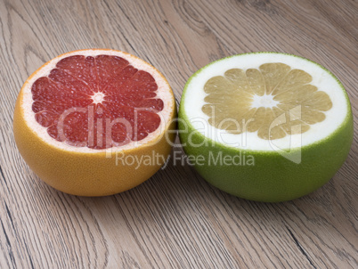 Halves of Green Sweetie and Red Grapefruit on wooden background.