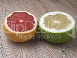 Halves of Green Sweetie and Red Grapefruit on wooden background.