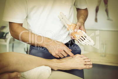 Physiotherapist explaining feet model to patient