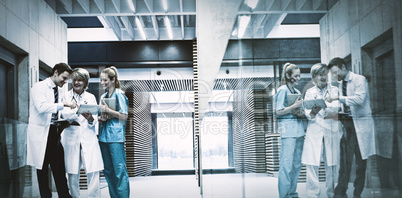 Medical team discussing over digital tablet in corridor