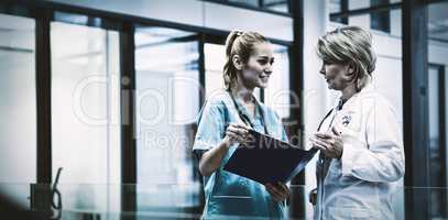 Female doctor and nurse discussing over a medical report