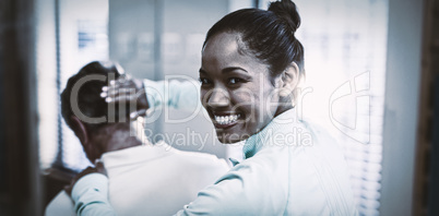 Rear view of portrait of smiling female therapist giving neck massaging to senior male patient