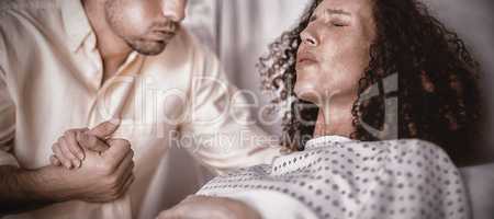 Man comforting pregnant woman during labor in ward