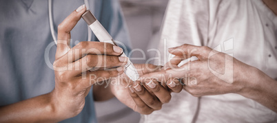 Mid section of doctor examining pregnant womans blood sugar