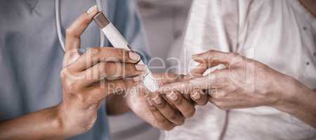 Mid section of doctor examining pregnant womans blood sugar