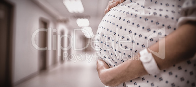 Mid section of pregnant woman standing in corridor