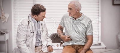 Senior man showing stomach ache pain to doctor