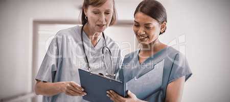 Nurse and doctor discussing over clipboard