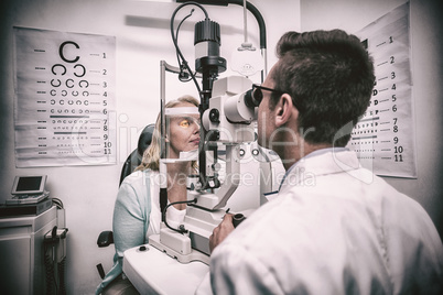 Optometrist examining female patient on slit lamp