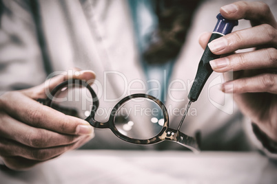 Optician repairing spectacles with tool