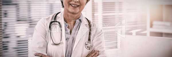 Portrait of a smiling female doctor standing with arms crossed