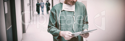 Surgeon checking report in corridor