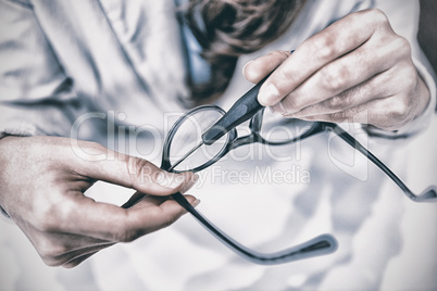 Optician repairing spectacles with tool