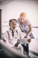 Male doctor with nurse talking over digital tablet