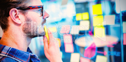 Thoughtful man reading sticky notes on the glass wall Thoughtful man reading sticky notes on the glass wall