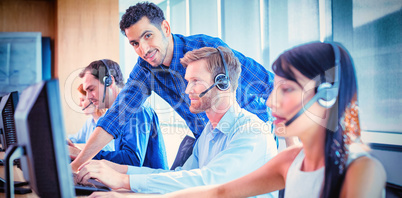 Male supervisor assisting telemarketer at call center