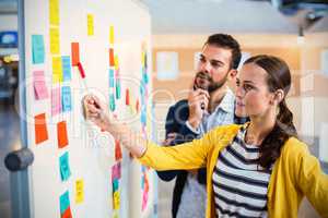 Young coworkers discussing over adhesive notes