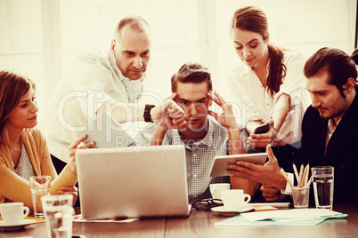 Irritated businessman in between coworkers showing technologies