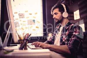 Creative businessman using computer while listening music