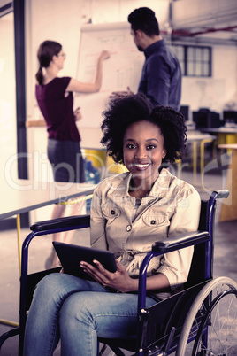 Portrait of smiling disabled business executive in wheelchair using digital tablet