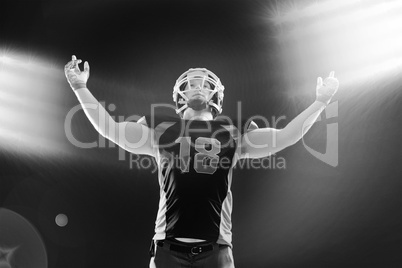 American football player standing against black background