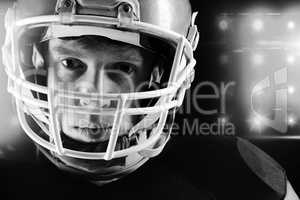 American football player in helmet standing against black background