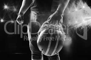 American football player standing with helmet against black background