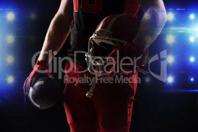American football player standing with helmet and rugby ball