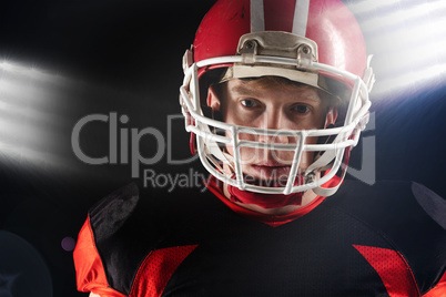 American football player in helmet standing against black background