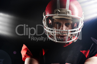 American football player in helmet standing against black background