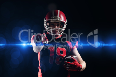 American football player in helmet holding rugby ball and pointing