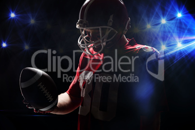 American football player with helmat looking at rugby ball