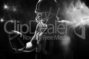 American football player with helmat looking at rugby ball