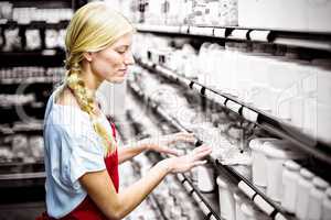 Female staff checking grocery products in shelf