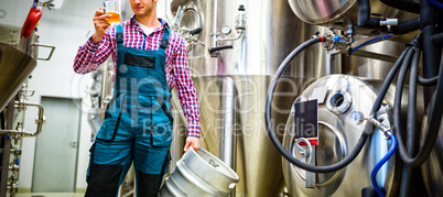 Brewer holding keg and testing beer