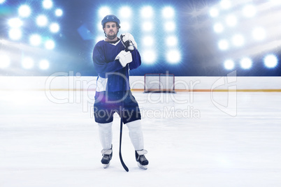 Composite image of hockey player with hockey stick standing on rink
