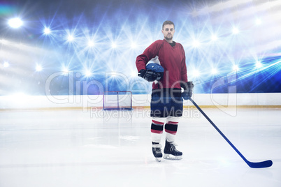 Composite image of portrait of ice hockey player holding helmet and stick