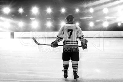 Composite image of hockey player with hockey stick standing on rink