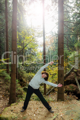 Woman is doing gymnastics in the forest